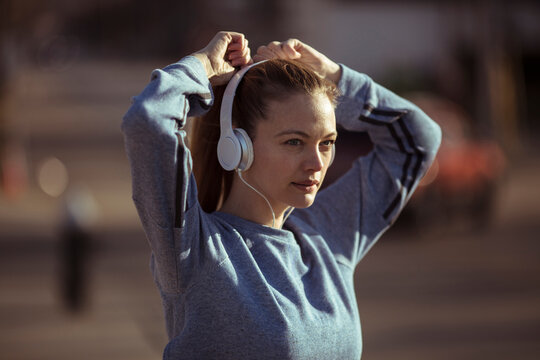 Woman athlete adjusting headphones before outdoor run