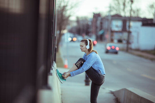Young woman stretching before a run on city sidewalk