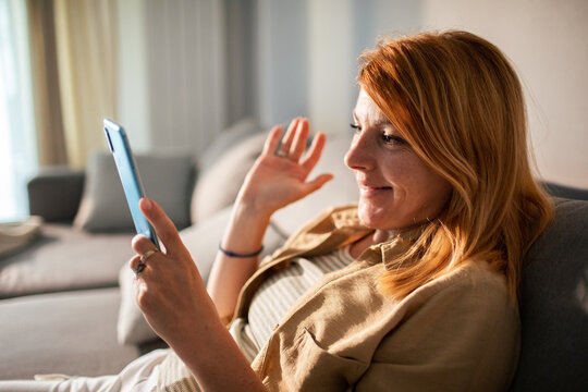 Smiling woman making video call on smartphone at home