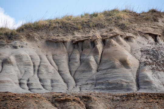 Severe soil erosion on a badlands hillside with a grassy peak