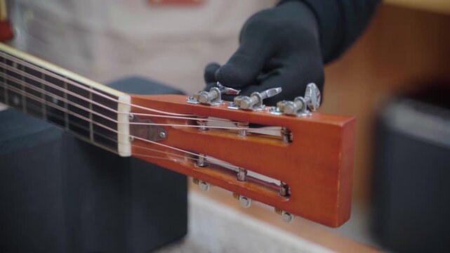 Guitar Technician Tuning Electric Guitar by Adjusting Tuning Pegs
