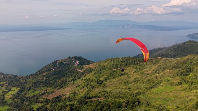 Dramatic Aerial View Over Coast. Energetic Aerial Shot Capturing Vibrant Red Glider Over Toba Lake