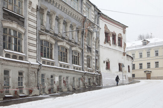 View of historic weathered buildings with arched windows and a person walking on a snow-covered street during winter Moscow, Moscow, Russia.