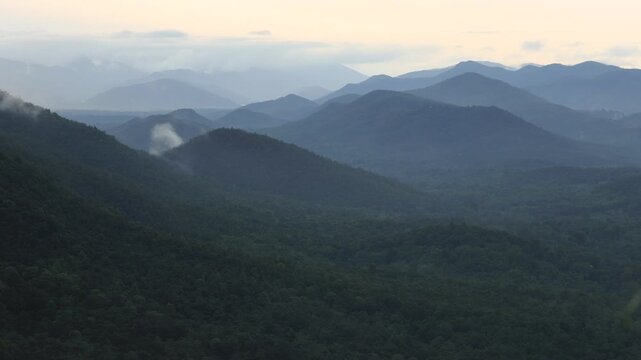 A nature-themed video background from a high mountaintop, offering panoramic views of the surrounding landscape, mist, trees, sunset, and cool, refreshing air during an adventurous travel experience.