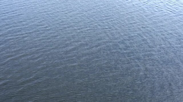 Grey blue river surface with small wind ripples, top view, abstract background