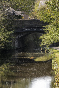 View of the historic Joseph Clayton stone bridge spanning the Lancaster Canal surrounded by lush green trees and calm water reflections Lancaster, England, United Kingdom.
