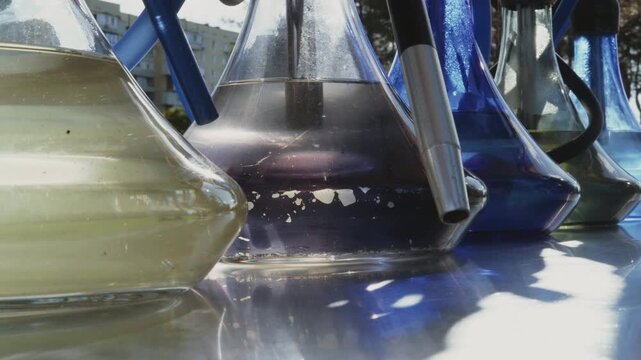 Close-up, hookahs filled with water stand on a counter in the park, glowing with the setting sun