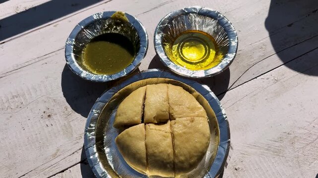 traditional himachali siddu meal served with ghee and curry in disposable plates