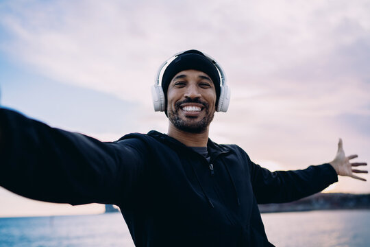 Portrait of a smiling man in winter athletic wear posing for camera while take selfie photo, happy athlete enjoying an outdoor cardio session in city, fitness motivation and urban wellness