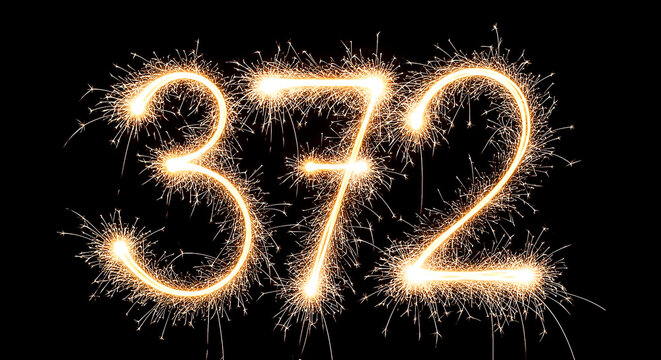 Vibrant sparklers forming the number 372 in a celebratory fireworks display, glowing brightly against a dark night sky.