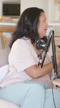 Vertical video: Hearing cue, host tapping tablet, using mic on sofa, pausing then looking shocked