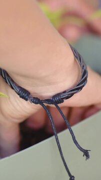 Vertical video: Hand reaching with cord on rim, tamping soil to steady two plants in pot using tool