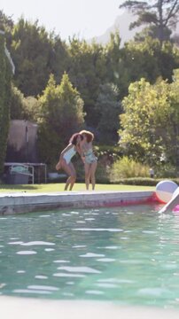 Vertical video: Stepping girls touching heads and whispering secrets at home pool, swimwear, float