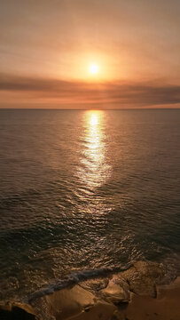 Golden sunset over calm ocean horizon with sun reflection on water