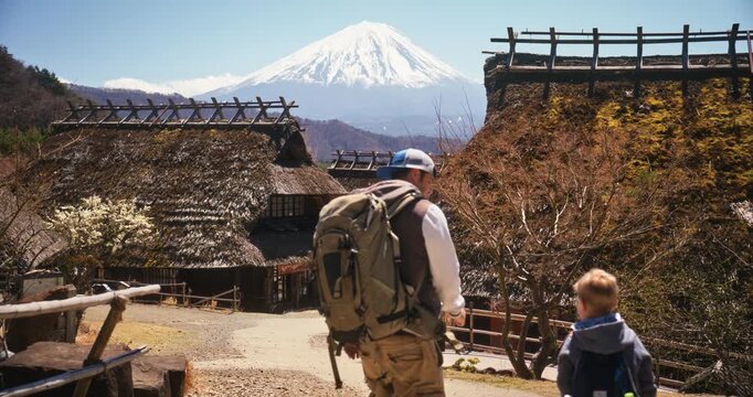 Father and son walking back and forth through ancient Japanese village with distant Mt. Fuji in background