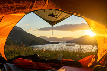 View from a tent overlooking a serene lake and mountains at sunset. © Rawpixel.com