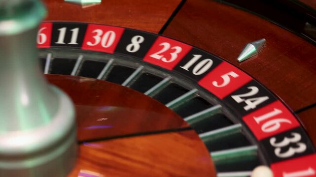 A rotating casino roulette wheel displays a white ball positioned in pocket 1 while the spindle stands at the center of the circular track. 
