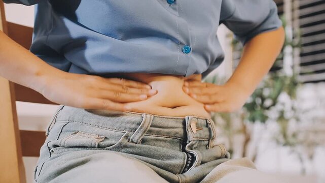 Overweight woman hand pinching excessive belly fat on gray background, Healthy concept