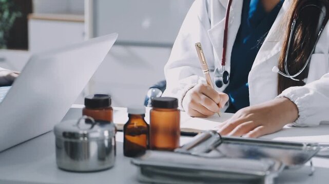 Brunette female clinician in lab coat pointing at laptop screen while making presentation of medical data to group of intercultural colleagues