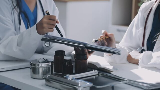 Brunette female clinician in lab coat pointing at laptop screen while making presentation of medical data to group of intercultural colleagues