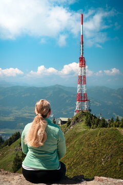 Female hiker admiring a telecommunication tower on the &Uuml;belhorn at Gr&uuml;nten mountain ridge near Sonthofen ideal for technology marketing