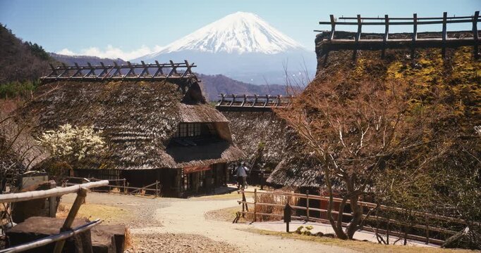 Son and father walking forward and backwards through ancient Japanese village with view of Mt. Fuji