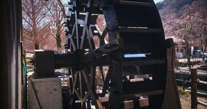 Japanese village mill with distant cherry blossoms - steady cam shot
