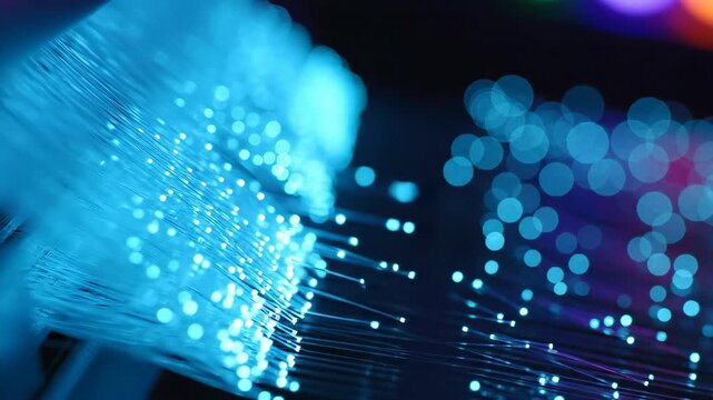 Glowing blue fiber optic cables transmitting data. Close up of illuminated filament strands used for high speed internet networking and digital communication tech