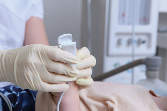 Doctor installs device to measure oxygen levels and pulse. Pulse oximeter is located on child's fingers. Child is under anesthesia before operation. Concept of modern medicine