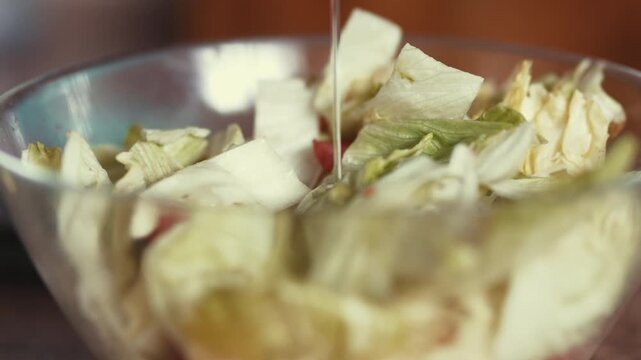 Close Up of Pouring Olive Oil onto Fresh Iceberg Lettuce Salad Leaves and Cut Tomatoes
