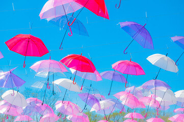 Fototapeta premium Beautiful umbrella sky art installation in a lush green garden at Tokachi Hills under a clear blue sky, Hokkaido, Japan.