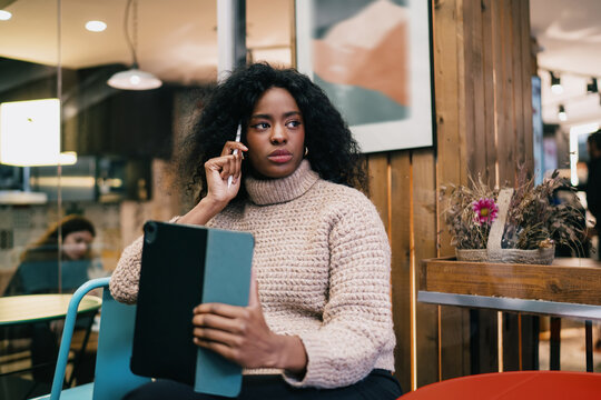 Financial freedom digital nomad tablet analysis task. Serious African American female freelancer looking away thinking over corporate business project data solution, authentic representation