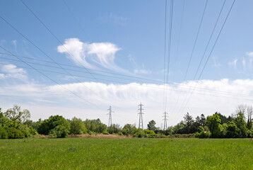 Obraz premium Pylons and overhead cables above a lush meadow in Geispolsheim, France