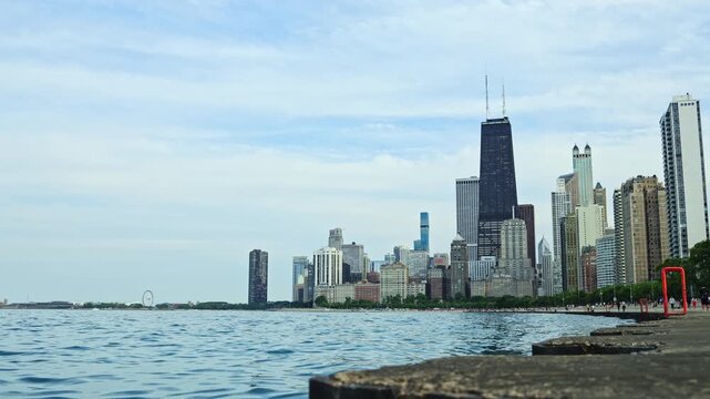Lake Michigan is in view with the Chicago skyline noticeable on the shore. Buildings rise high against a clear sky. The scene shows water ripples and distant attractions.