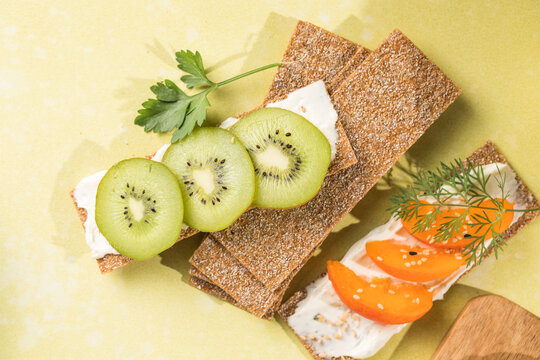 Fresh crunchy rye crispbreads with different toppings on green table, top view