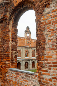 View through arched brick ruin to historic redbrick courtyard and arcade