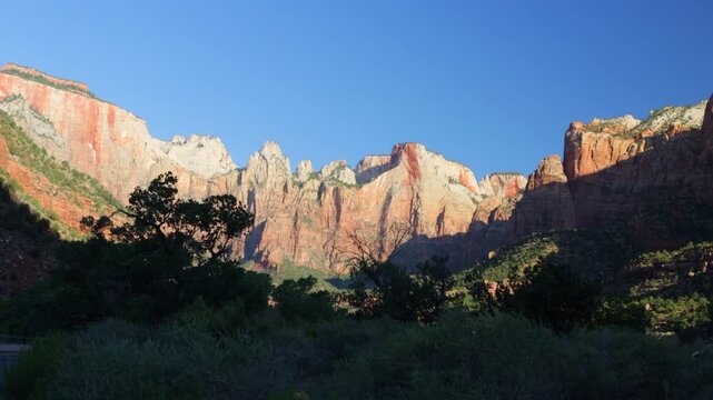 Dawn light on the rocky bluffs and windblown trees of Zion National Park in southern Utah