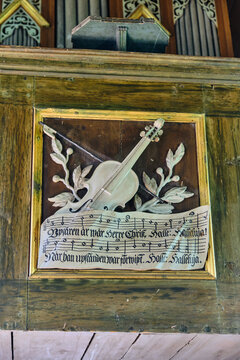 Lund, Sweden - 02 August 2025: View of a wooden relief carving of a violin and sheet music on an old organ or pulpit at Kulturen open air museum.