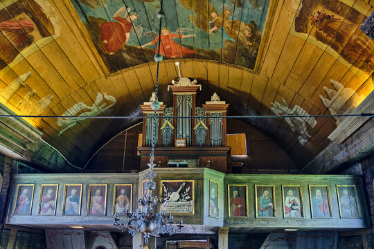 Lund, Sweden - 02 August 2025: View of the interior of Bosebo Church at Kulturen open air museum featuring a painted wooden ceiling, pipe organ, and historic gallery portraits.