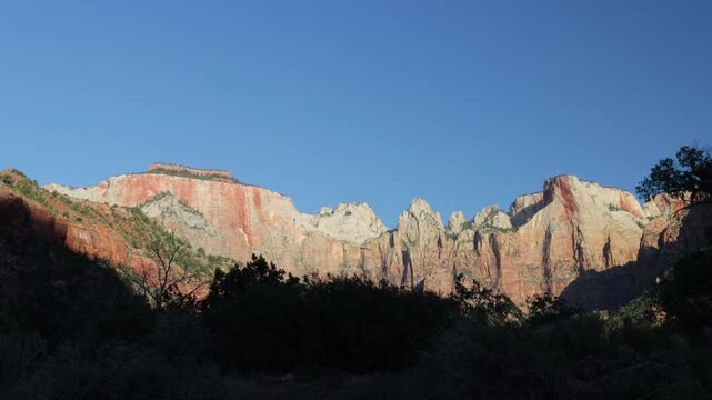 Dawn light on the rocky bluffs and windblown trees of Zion National Park in southern Utah
