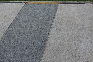 Fototapeta premium Textured concrete pathway with contrasting grey and light grey sections and yellow border