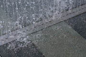 Close-up of water cascading over textured stone surfaces in a modern fountain design © khomkrit