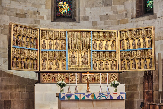 Lund, Sweden - 02 August 2025: View of the ornate golden altarpiece inside Lund Cathedral featuring intricate wood carvings of saints and religious figures against stone walls.