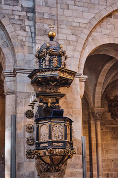 Lund, Sweden - 02 August 2025: View of the ornate Renaissance pulpit inside Lund Cathedral featuring intricate carvings and gold leaf details against stone arches.