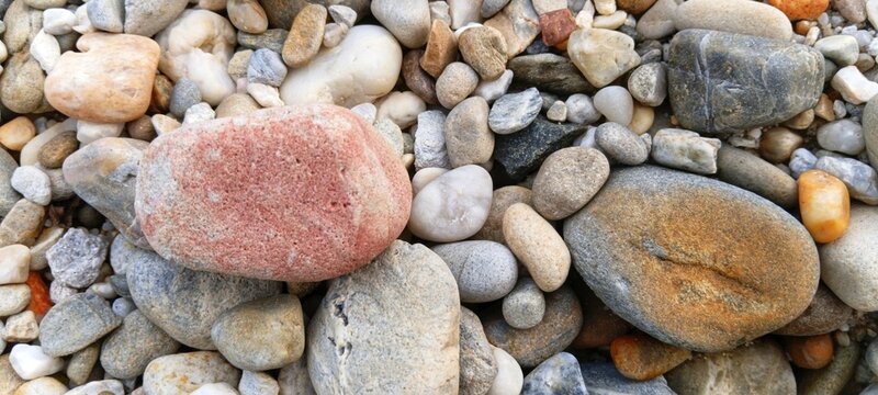 Smooth river stones creating a clean border around a sandy center, providing elegant copy space for summer travel advertisements