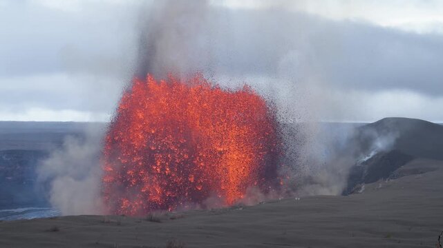 View of a powerful lava fountain erupting with smoke and ash from Halema'uma'u Crater under a cloudy sky Hawaii County, Hawaii, United States.