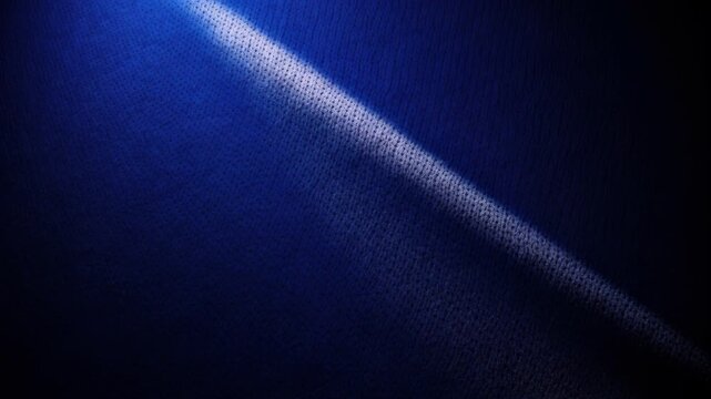 Diagonal Light Ray on Blue Textured Surface: A single, sharp ray of white light cuts diagonally across a deep blue textured surface, creating a dramatic contrast and highlighting the fabric's weave.