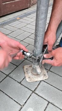 Workers are tightening the fasteners of metal scaffolding with a wrench.