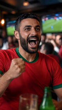 Excited soccer fan celebrating a goal while watching game at bar with friends