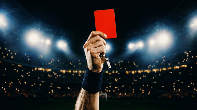 Referee's stern decision a red card raised high against the dramatic stadium lights, symbolizing an expulsion from the intense sports competition